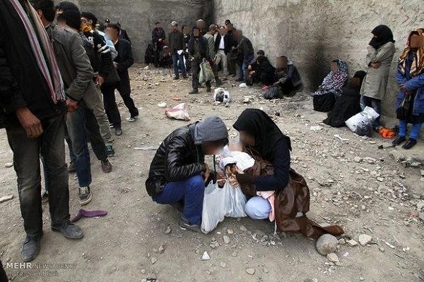 A group of people surround two women kneeling down on the ground. Photo Credits: Saied Goli/Mehr News Agency