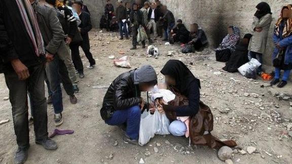 A group of people surround two women kneeling down on the ground. Photo Credits: Saied Goli/Mehr News Agency