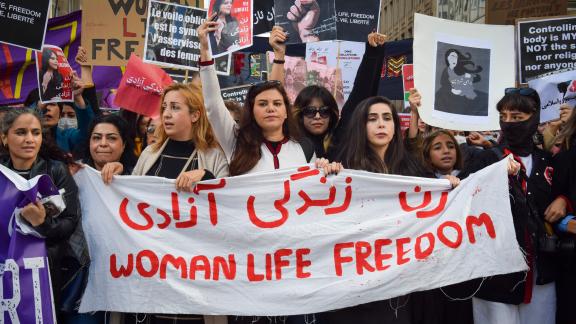 A group of Iranian women at a protest holding a white banner that reads "Woman, Life, Freedom" in red. | Photo by: Viktoria Bykanova/Shutterstock