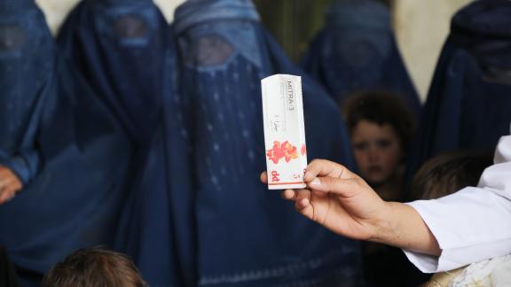 A midwife holds a medicine pack as the community members look on.
